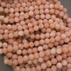 Multiple strands of matte peach moonstone round beads displaying warm blush pink and creamy peach color variations.