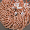 Natural peach moonstone beads featuring soft pastel colors, delicate white banding, and a smooth matte surface.