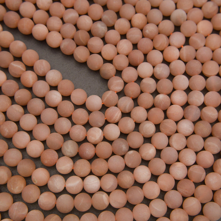Peach moonstone round gemstone beads with subtle natural shimmer and warm pink tones for handmade jewelry.