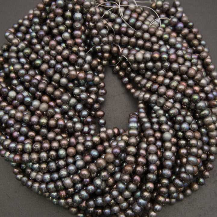 A coiled strand of iridescent freshwater pearl beads on a dark gray background.