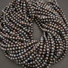 A coiled strand of iridescent freshwater pearl beads on a dark gray background.