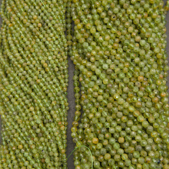 Close-up of multiple strands of faceted green beads, likely seed beads for jewelry making, arranged vertically.