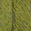 Close-up of multiple strands of faceted green beads, likely seed beads for jewelry making, arranged vertically.