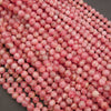 A pile of small round pink beads with white marbled streaks, photographed close-up on a dark gray surface.