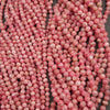A close-up of many small round beads in a dusty pink color with white marbling, arranged in vertical strands.