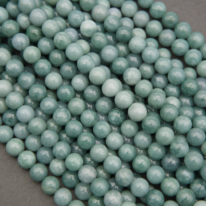 Close-up of polished Guatemalan jade gemstone beads showcasing delicate green marbling and natural color variations.