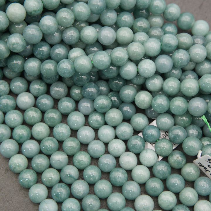 Natural Guatemalan jade beads featuring a polished surface and subtle cloudy green mineral patterns for jewelry making.