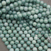Natural Guatemalan jade beads featuring a polished surface and subtle cloudy green mineral patterns for jewelry making.
