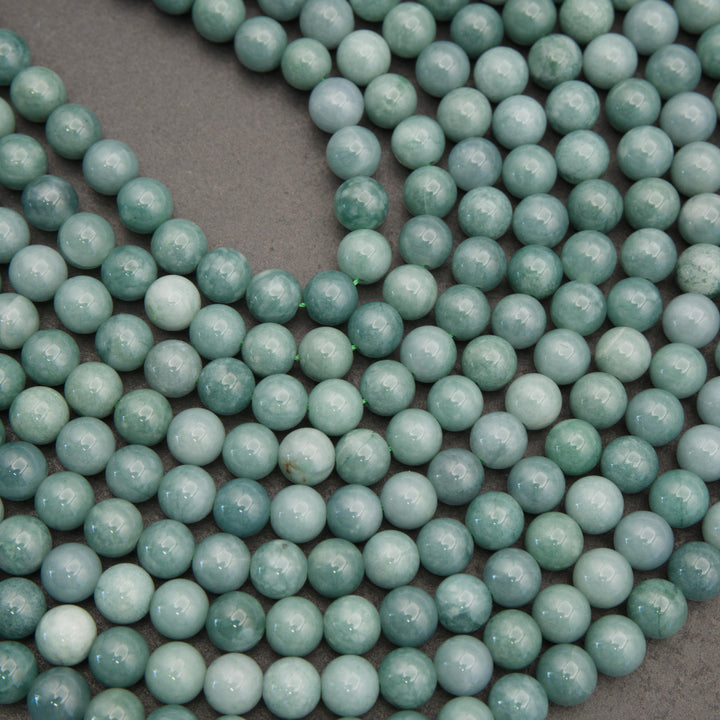 Close-up of Guatemalan jade round beads highlighting their glossy finish and varying shades of mint and blue-green.