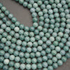 Close-up of Guatemalan jade round beads highlighting their glossy finish and varying shades of mint and blue-green.