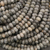 A close-up pile of oval stone beads in a marbled pattern of gray, white, beige, and black.