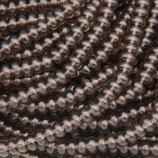 A close-up of many small oval beads strung on cords, showing a translucent smoky brown color with gray reflections.