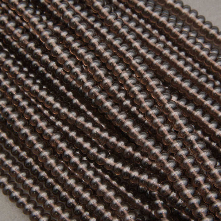 Close-up of multiple strands of small, round, metallic bronze beads arranged diagonally.