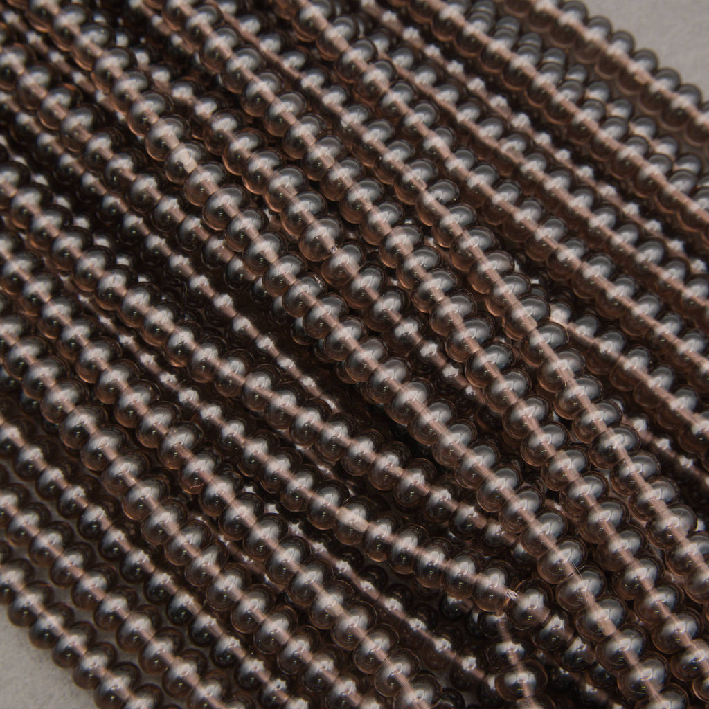 Close-up of multiple strands of small, round, metallic bronze beads arranged diagonally.
