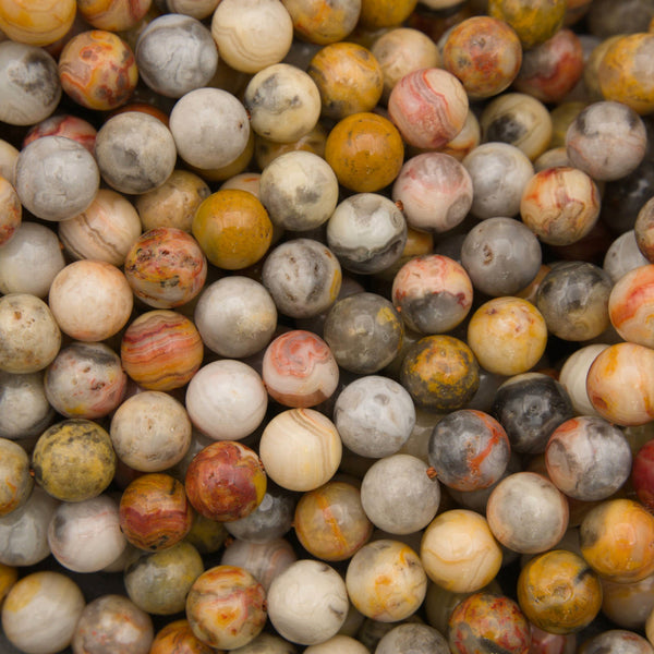 A close-up pile of round stone beads in mixed earthy colors including cream, gray, yellow, orange, and brown marbling.
