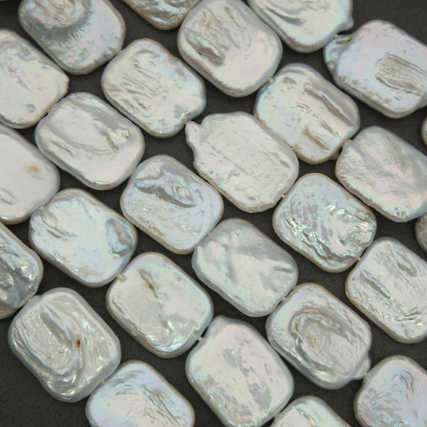 Close-up of rectangular, light-colored beads on a dark background