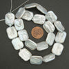 String of white baroque pearl beads with a penny for size comparison on a dark background