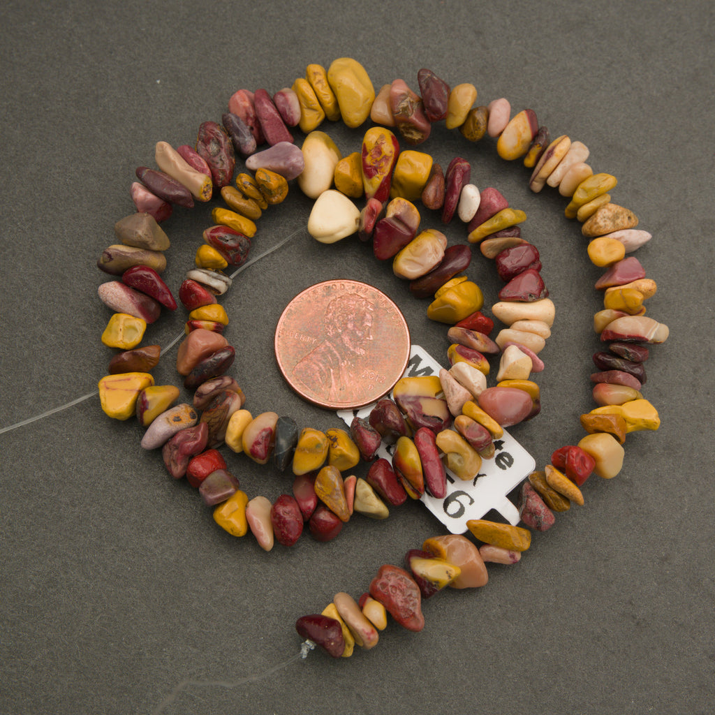 Necklace made of multicolored stones with a penny for scale on a gray background