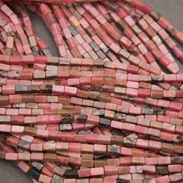 Natural rhodonite gemstone tube beads in warm salmon-pink shades with contrasting dark inclusions.