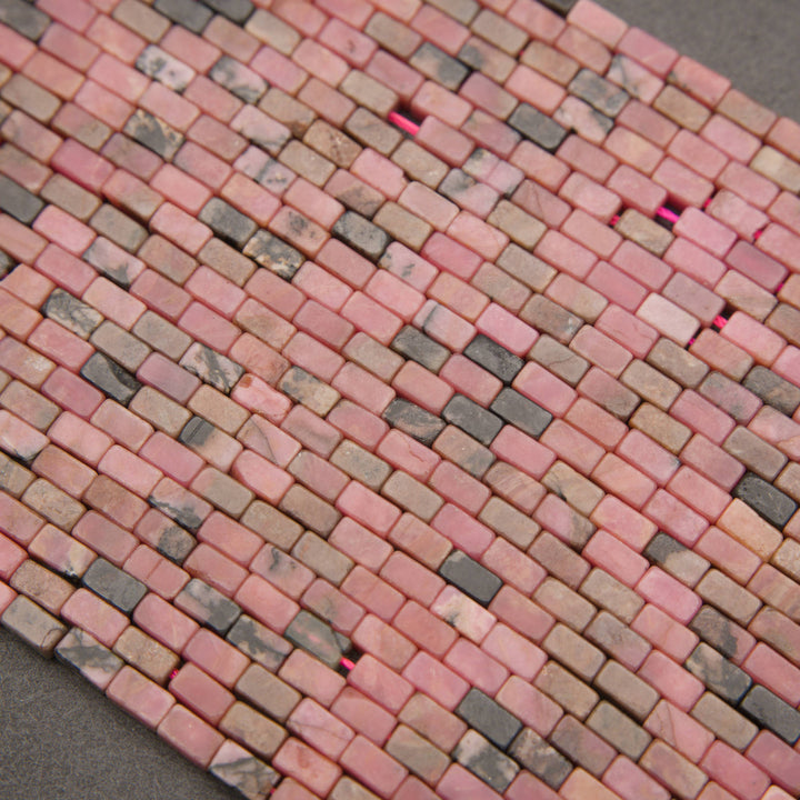 Strands of rectangular rhodonite beads with varied rosy-pink tones and earthy brown-gray patterns.