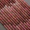 Close-up of pink and red gemstone beads on a gray surface
