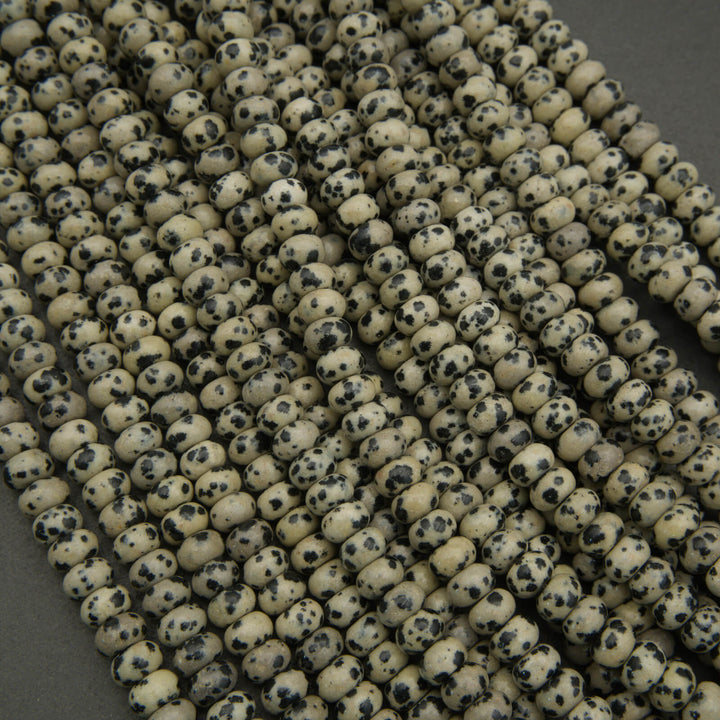Close-up of a string of small, round beads with black speckles on a dark background