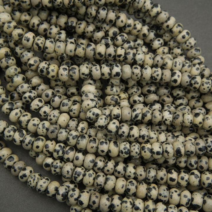 Close-up of a string of small, round beads with black speckles on a gray background