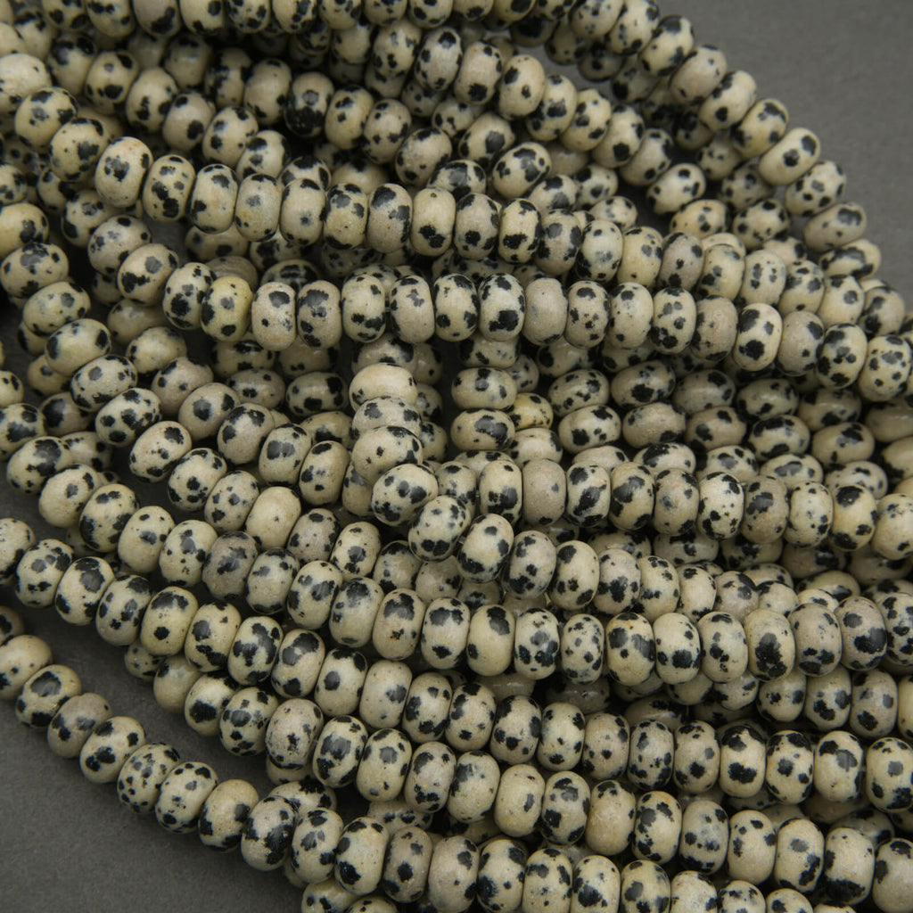 Close-up of a string of small, round beads with black speckles on a gray background