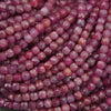 Close-up of faceted gemstone beads in a dusty rose pink color, arranged in overlapping rows.