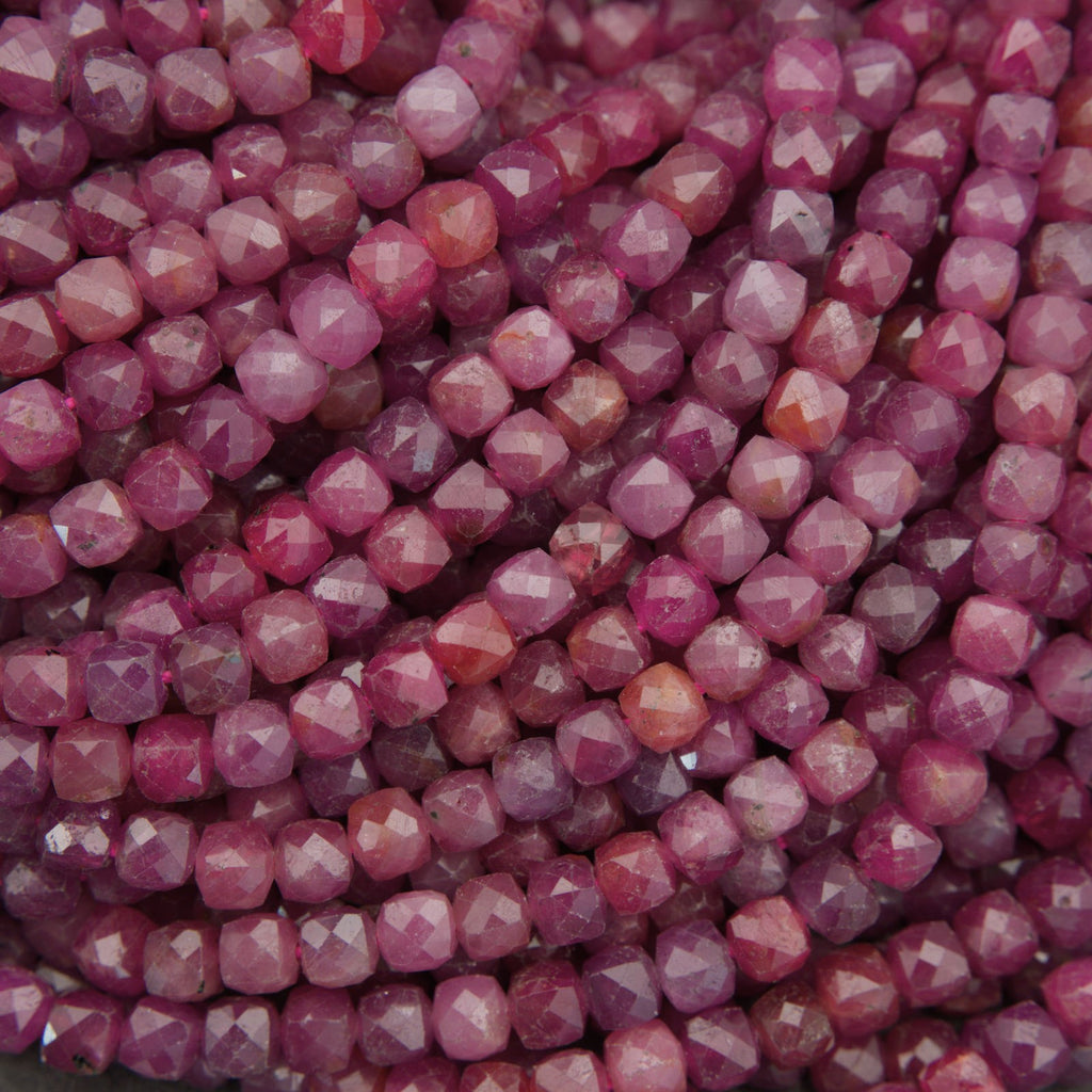 Close-up of faceted gemstone beads in a dusty rose pink color, arranged in overlapping rows.