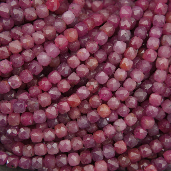 Close-up of faceted gemstone beads in a dusty rose pink color, arranged in overlapping rows.
