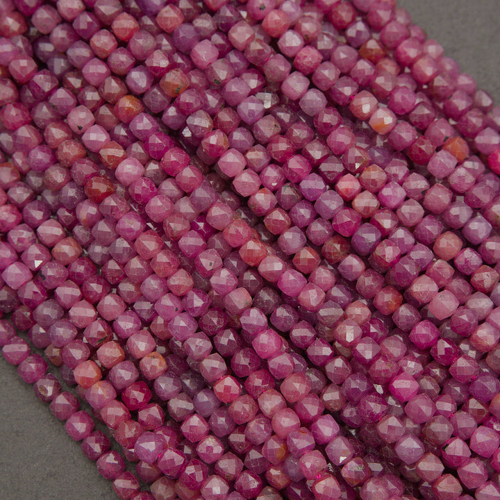 Faceted round beads in a vibrant magenta-pink color, arranged in parallel strands on a neutral gray background.