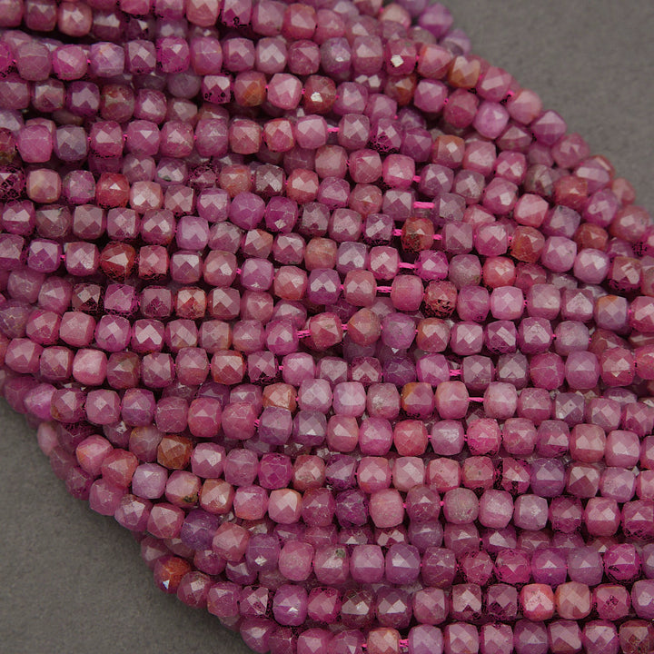 Faceted pink gemstone beads arranged in a curved stack on a neutral gray background.
