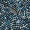 A close-up of many small round blue marbled beads scattered across a gray surface, with no person, animal, or real environment visible.