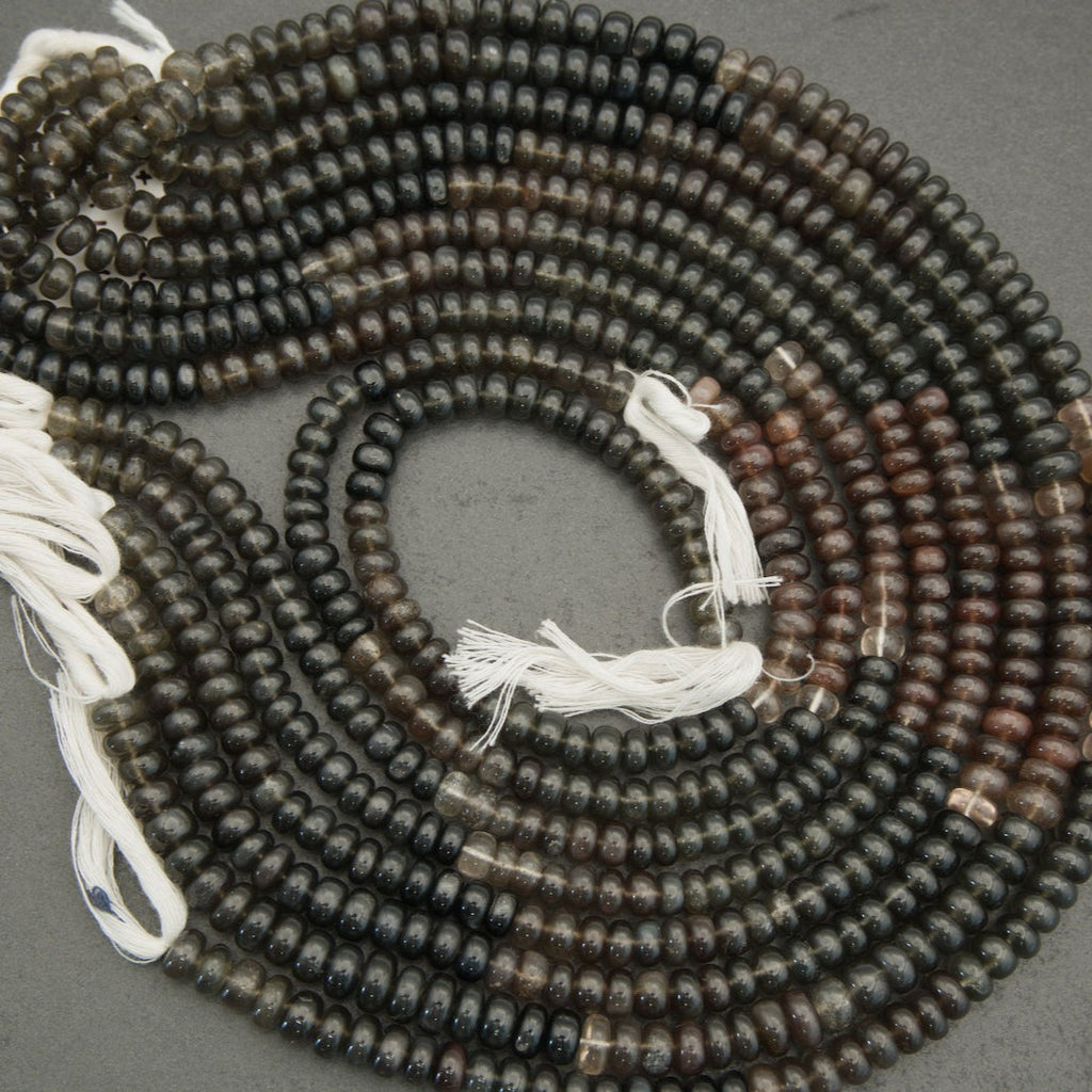 String of black and brown beads with white tassels on a gray background