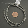 String of beads with a penny for scale on a gray background