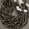 Multiple strands of dark pearls with price tags on a gray surface