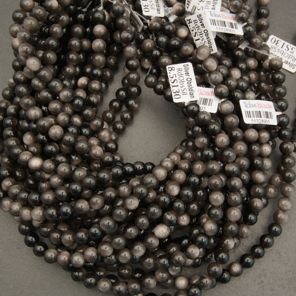 Multiple strands of dark pearls with price tags on a gray surface
