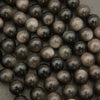 Close-up of dark brown glass beads on a textured surface
