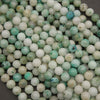 A heap of smooth round Sky Mountain Jade beads in creamy white and pale mint with teal flecks