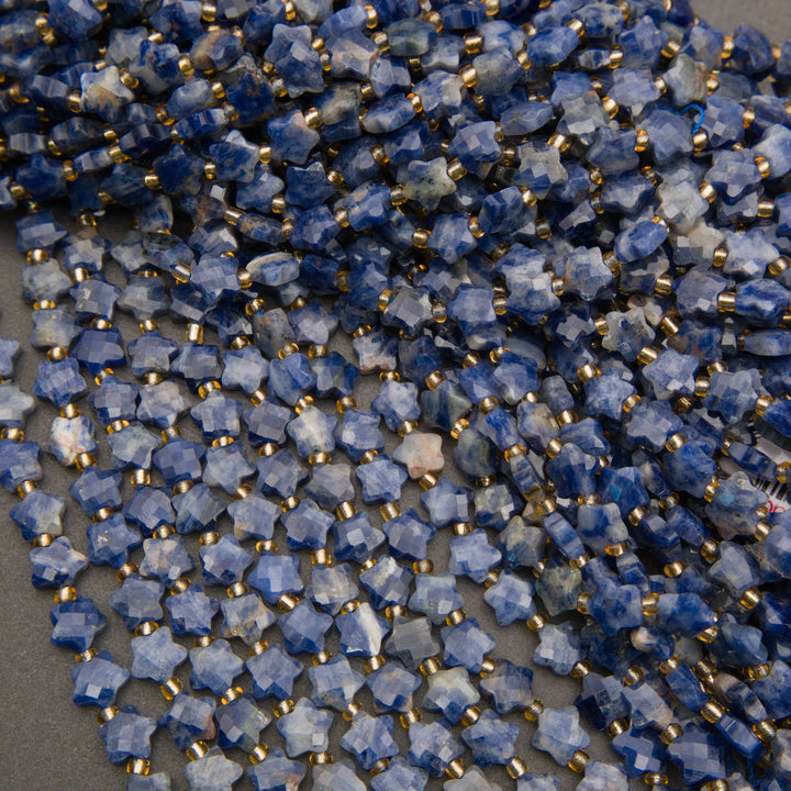 Rows of faceted snowflake sodalite star beads fanned out on a gray background