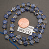 A strand of faceted snowflake sodalite star beads coiled around a penny for scale