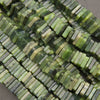 Close-up of multiple strands of rectangular faceted beads in shades of green, olive, and cream, arranged diagonally.
