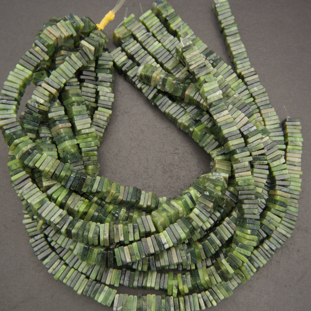 Green stone bead strands made of small rectangular disc-like beads, arranged on a dark gray background.