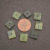 Eight small square green stone beads with a central hole, arranged in a circle around a copper penny on a dark gray background.