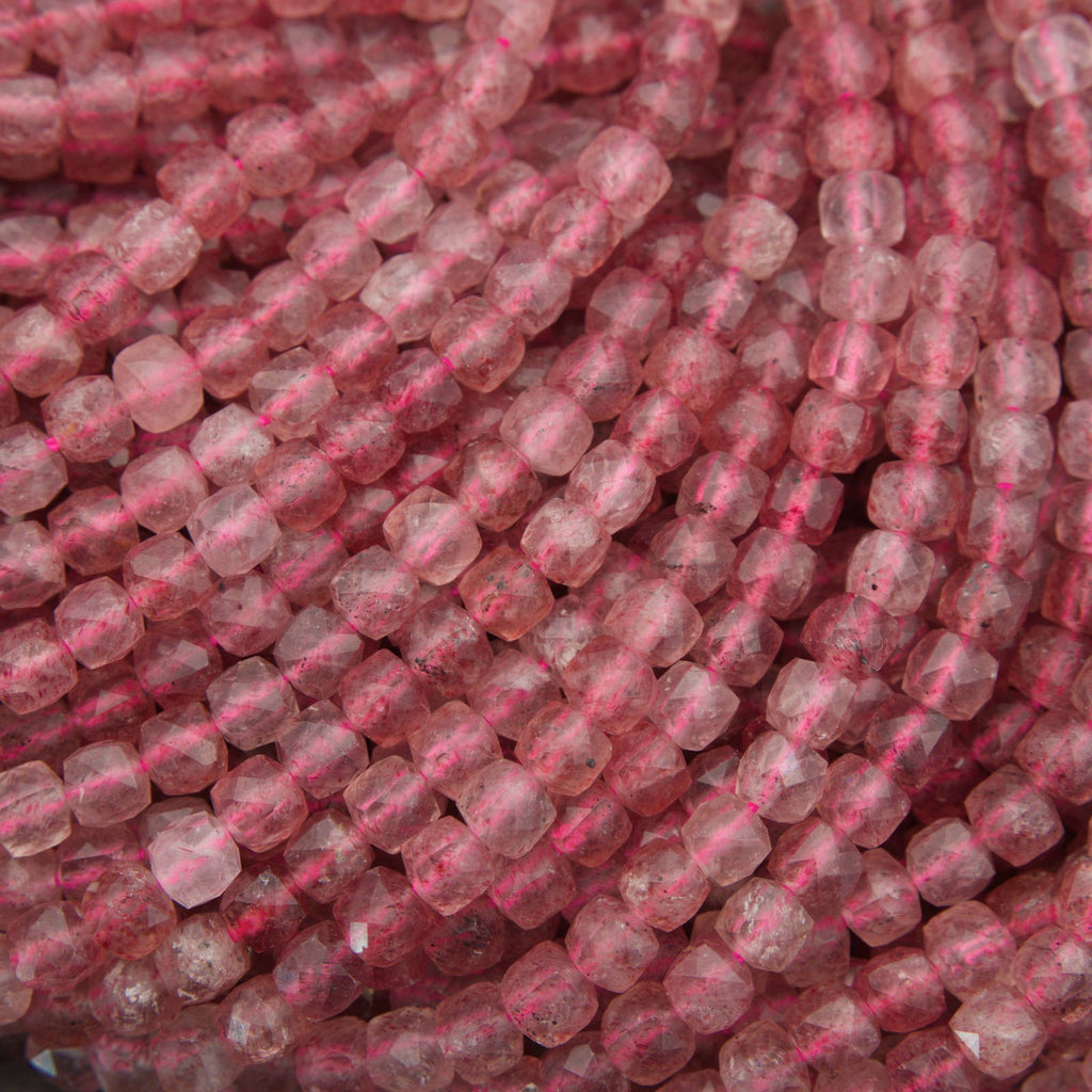 Close-up of strands of faceted pinkish-red beads, likely rose quartz, showing a translucent pink color with natural inclusions.