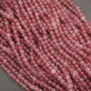 A close-up of multiple strands of faceted pink beads, likely rose quartz, arranged on a neutral gray background.