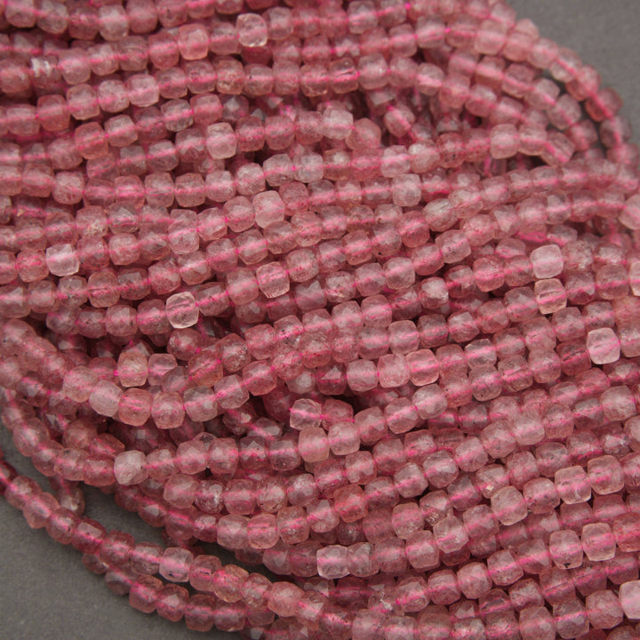 A close-up of a coiled bundle of small, faceted pink beads on a neutral gray background.
