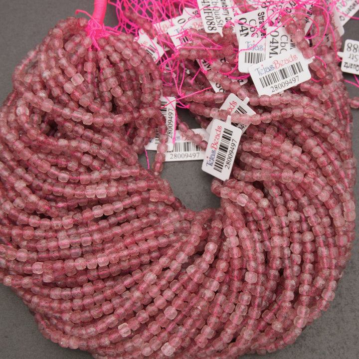 A close-up of a coiled bundle of small, faceted pink beads on a neutral gray background.