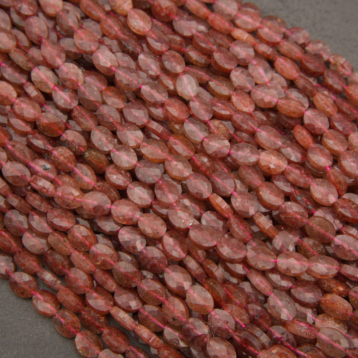 A heap of faceted strawberry quartz oval bead strands in soft pink to strawberry red